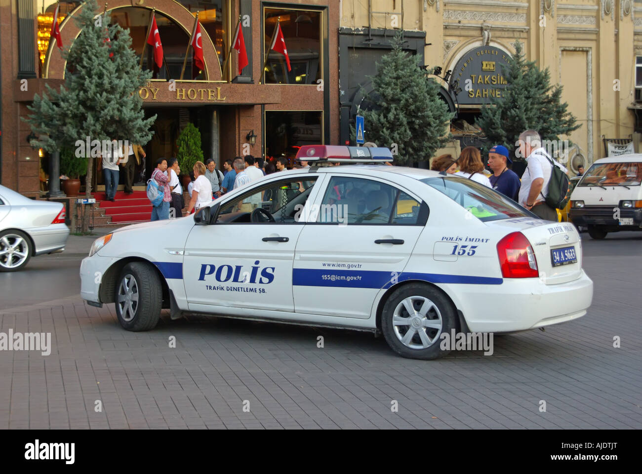 I turisti e la gente locale fuori da un hotel nella popolare Piazza Taksim hanno parcheggiato la macchina della polizia nelle prime ore della scena stradale della sera nella parte europea di Istanbul Turchia Foto Stock