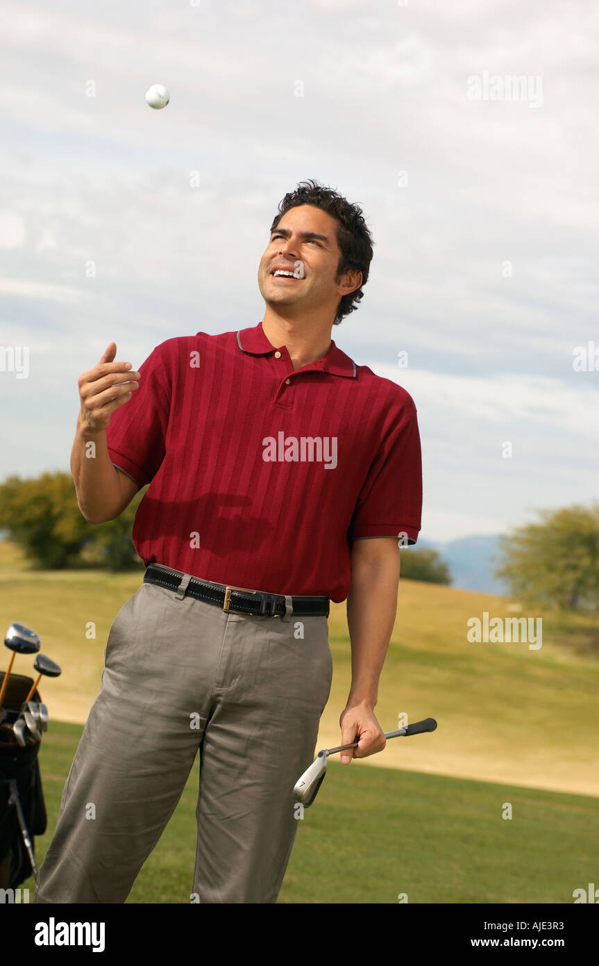 Il Golfer Holding Putter lanciare la pallina da golf in aria sul campo da golf Foto Stock