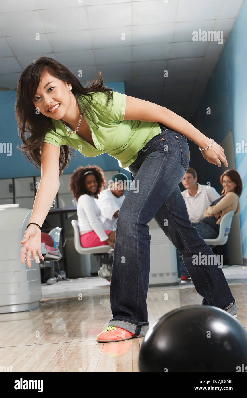 Giovane donna il rilascio di palla da bowling, ritratto Foto Stock