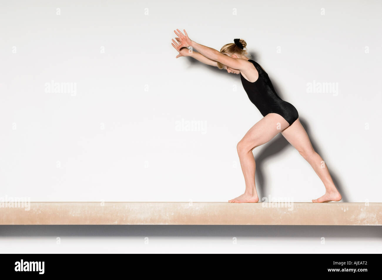 Ginnasta(13-15) sul fascio di equilibrio preparando a fare handstand, vista laterale Foto Stock