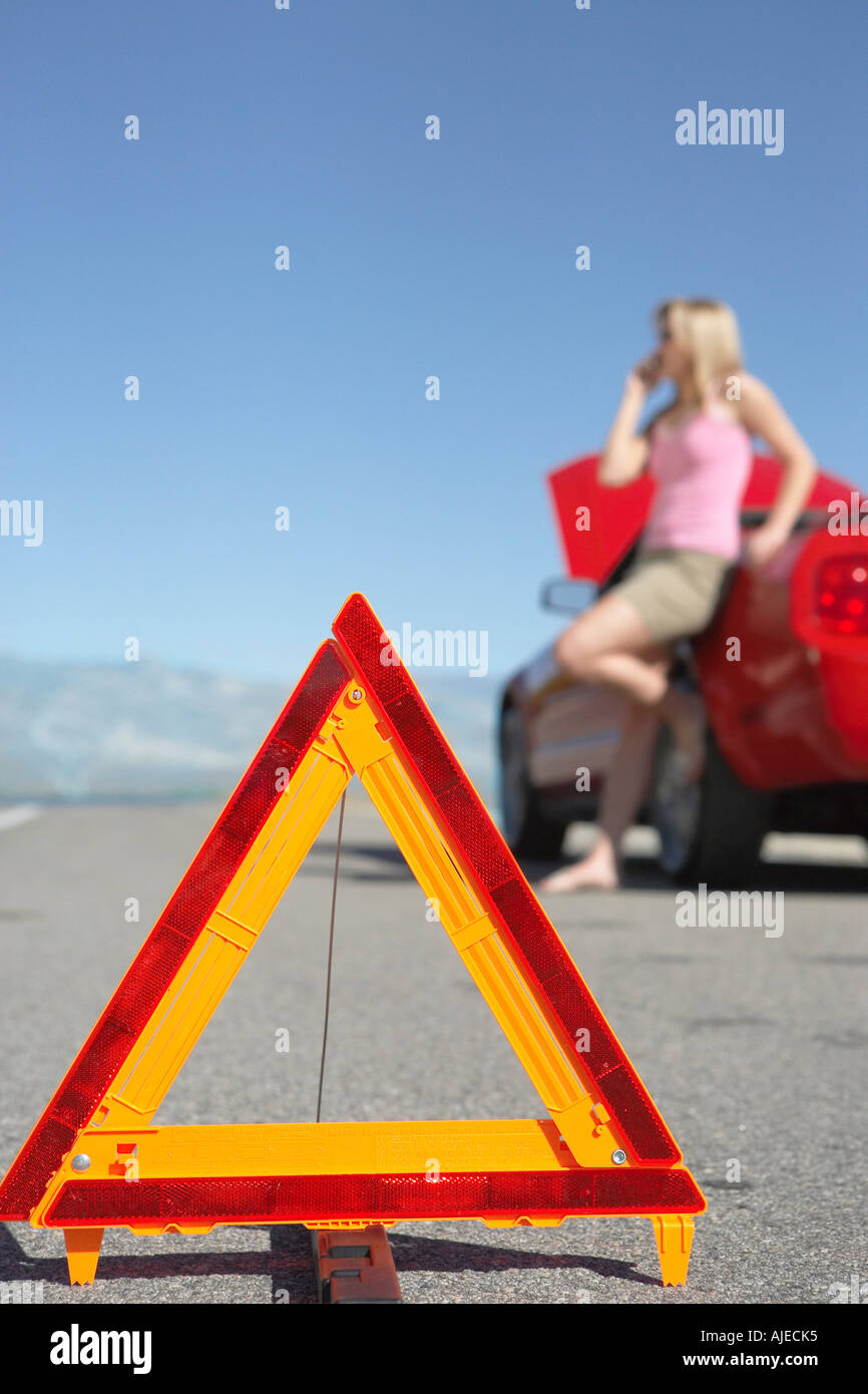 Il triangolo di avvertenza di fronte della donna sul telefono cellulare da auto sportiva rossa Foto Stock