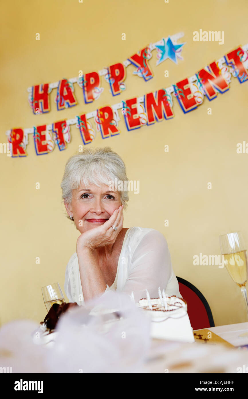 Donna seduta, mano sul mento in un partito di pensionamento Foto Stock