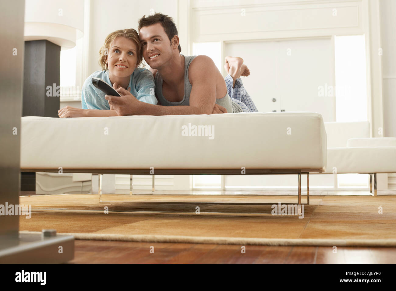 Giovane sul letto a guardare la televisione insieme, uomo con telecomando Foto Stock