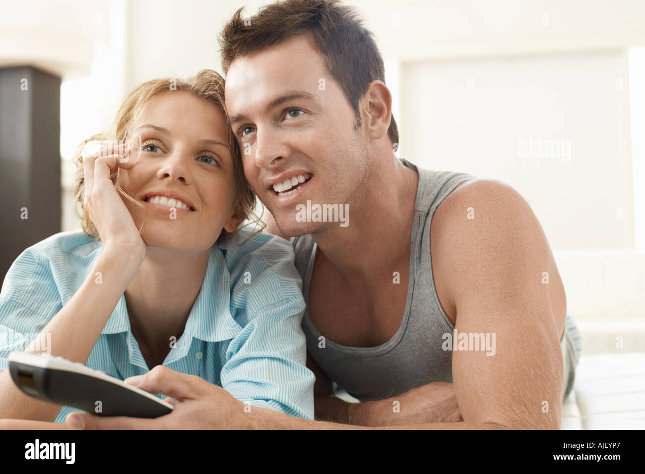 Giovane sul letto a guardare la televisione, uomo con telecomando Foto Stock