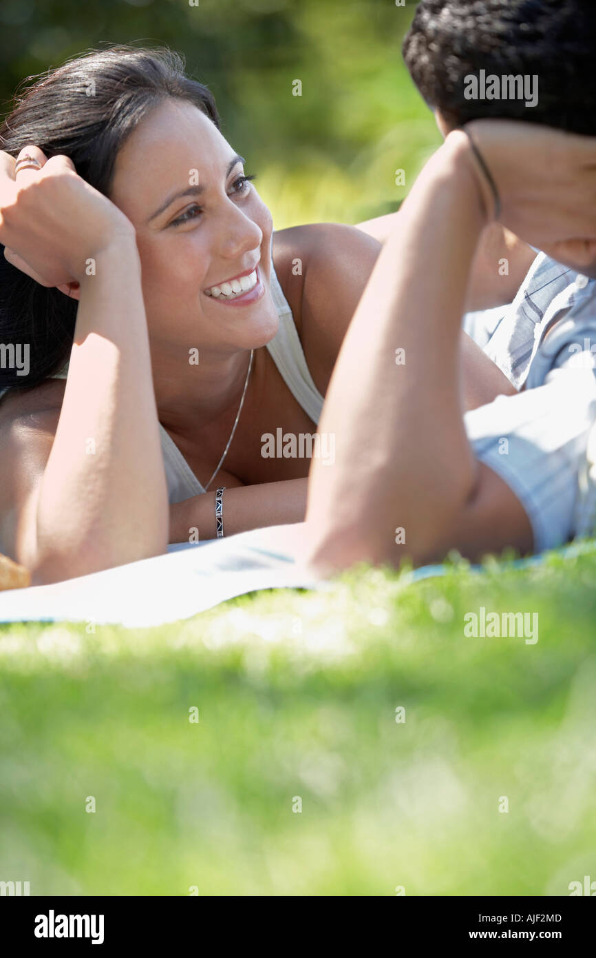 Paio di parlare faccia a faccia, giacente sul prato del parco Foto Stock
