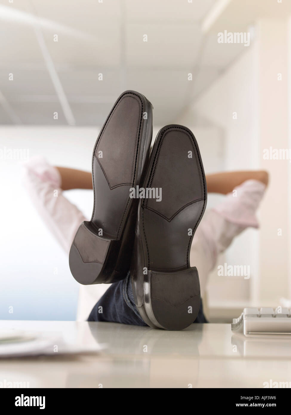 Imprenditore con piedi sulla scrivania, faccia oscurata Foto Stock