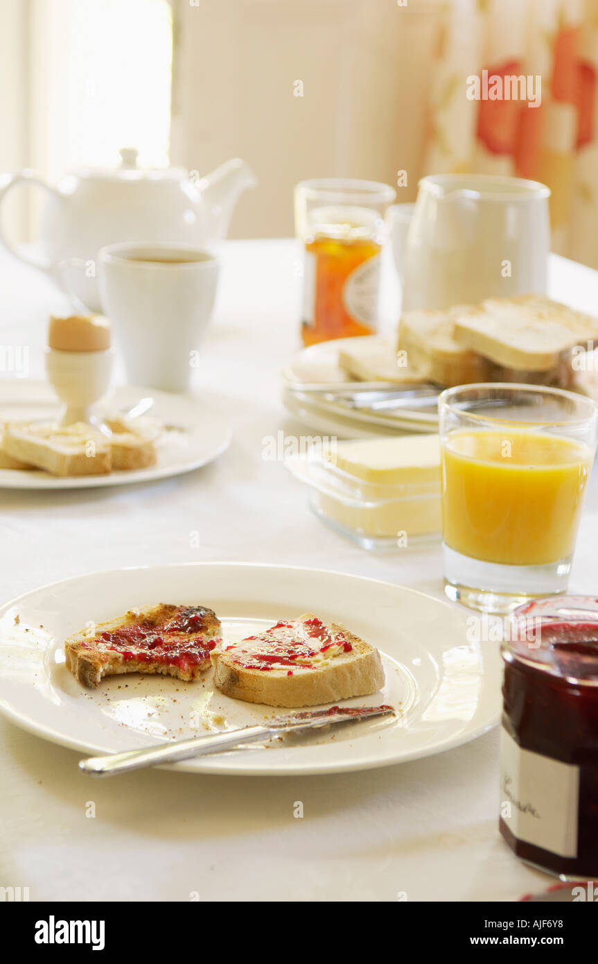 Piastra con semi-mangiato toast ricoperto di marmellata, sul tavolo per la prima colazione Foto Stock