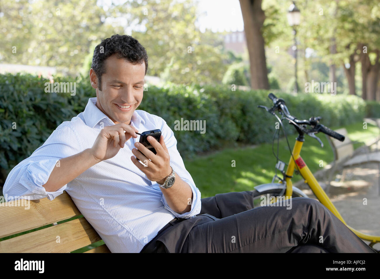 Imprenditore utilizzando Palm Pilot su una panchina nel parco Foto Stock