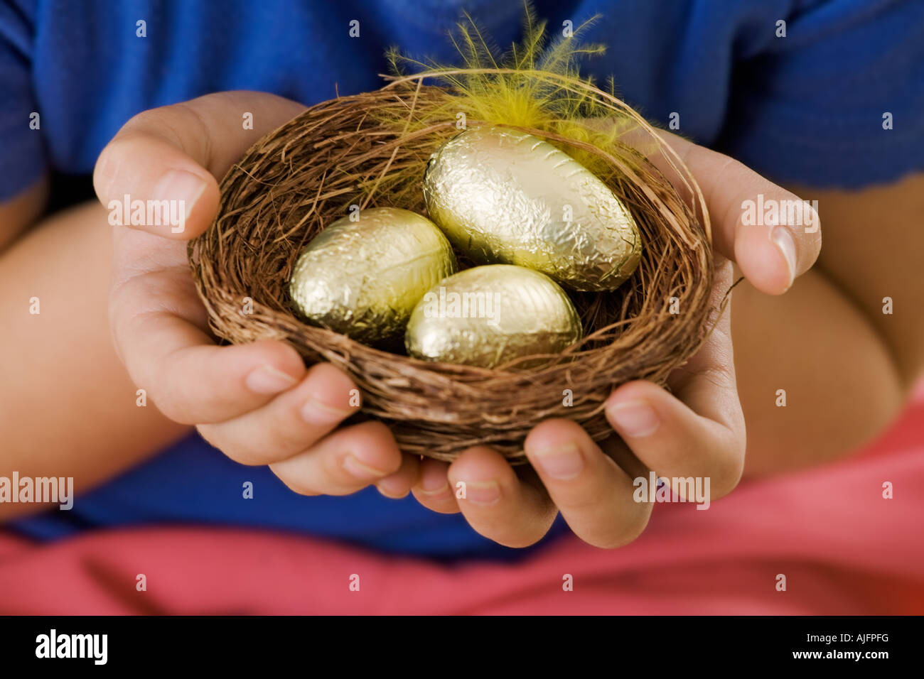 Bambino tenendo un cestello con golden uova di Pasqua mani solo Studio shot Modello rilasciato Foto Stock