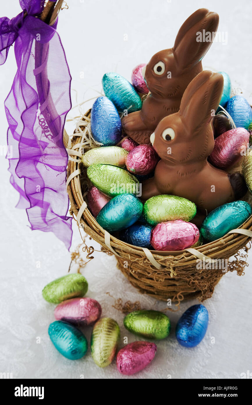 Uovo di Pasqua raccolta nel cesto di vimini con due conigli di cioccolato Studio shot Foto Stock