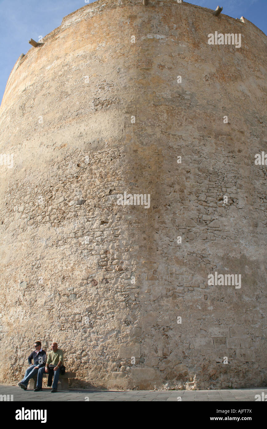 Due uomini relax al sole invernale al porto di Alghero, Sardegna, Italia Foto Stock