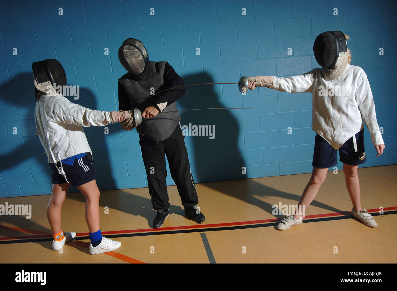 Due ragazze imparare l arte della scherma da un istruttore in una scuola di hall. Foto Stock