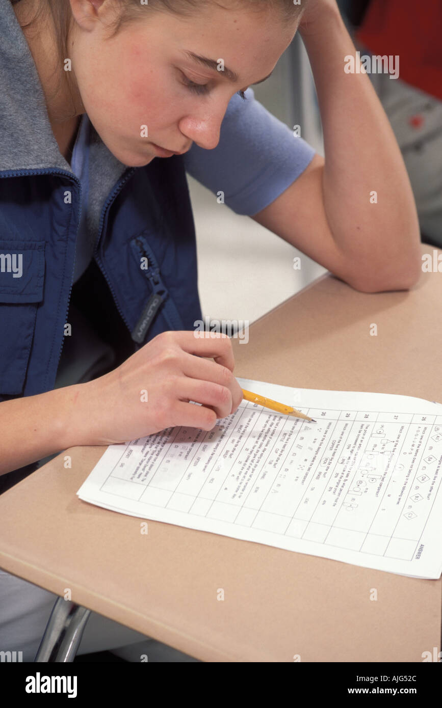 Caucasian female student Concentrating while taking test in middle school class Foto Stock