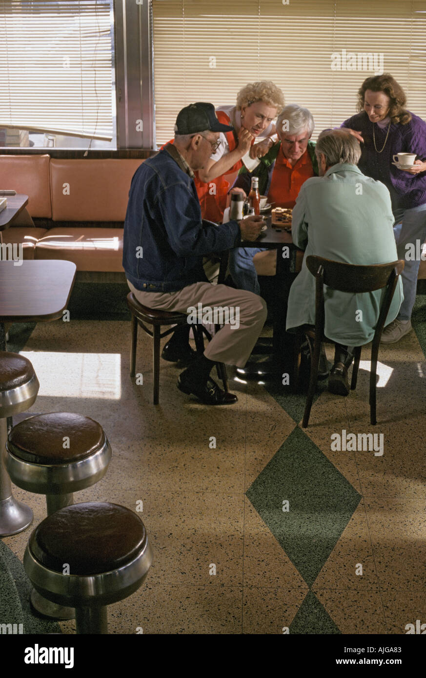 Seniors caucasica riuniti intorno ad un tavolo e giocare il gioco della dama in un diner Foto Stock