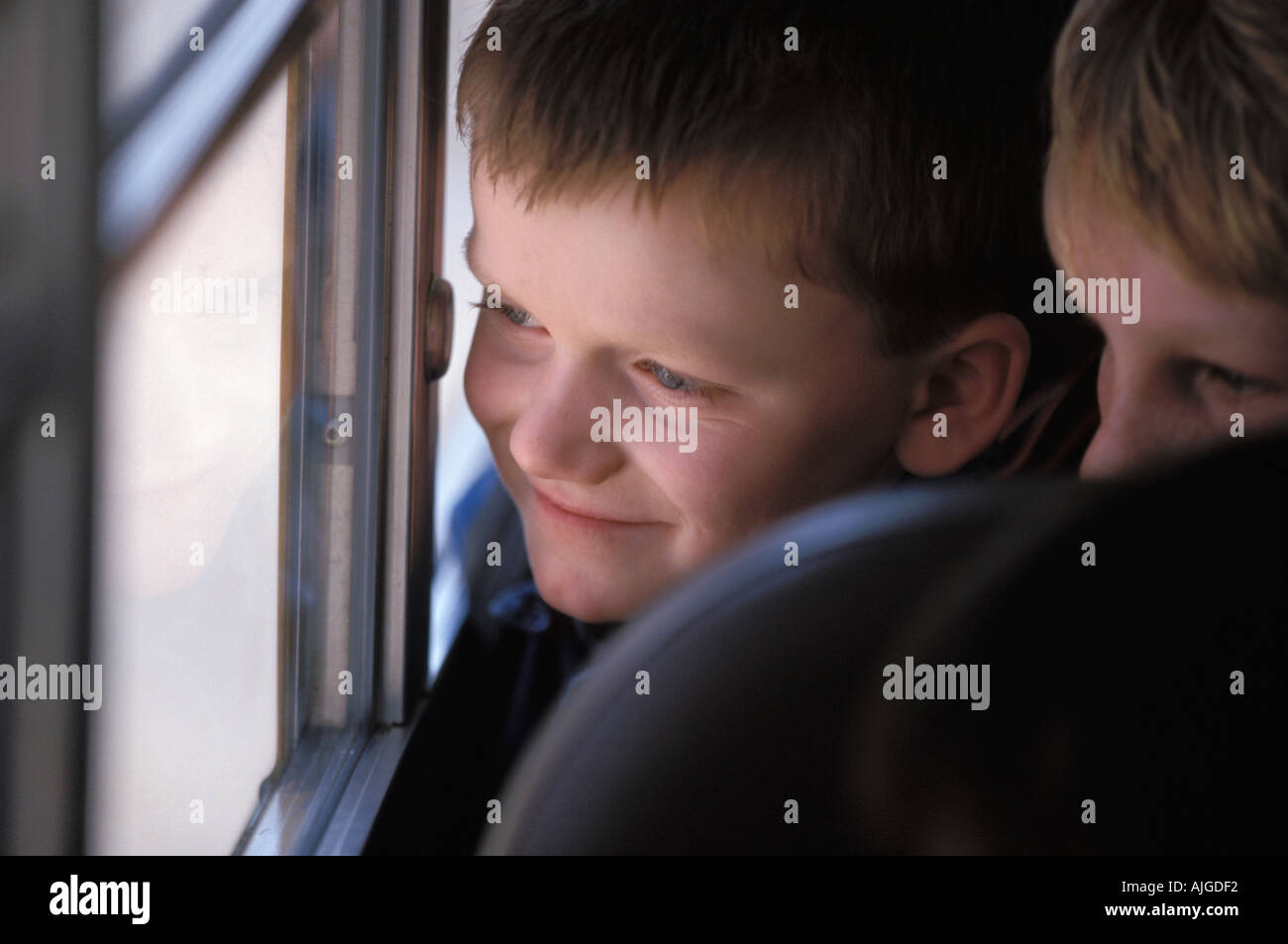 Un giovane ragazzo che guarda fuori dalla finestra mentre in sella a un bus di scuola Foto Stock