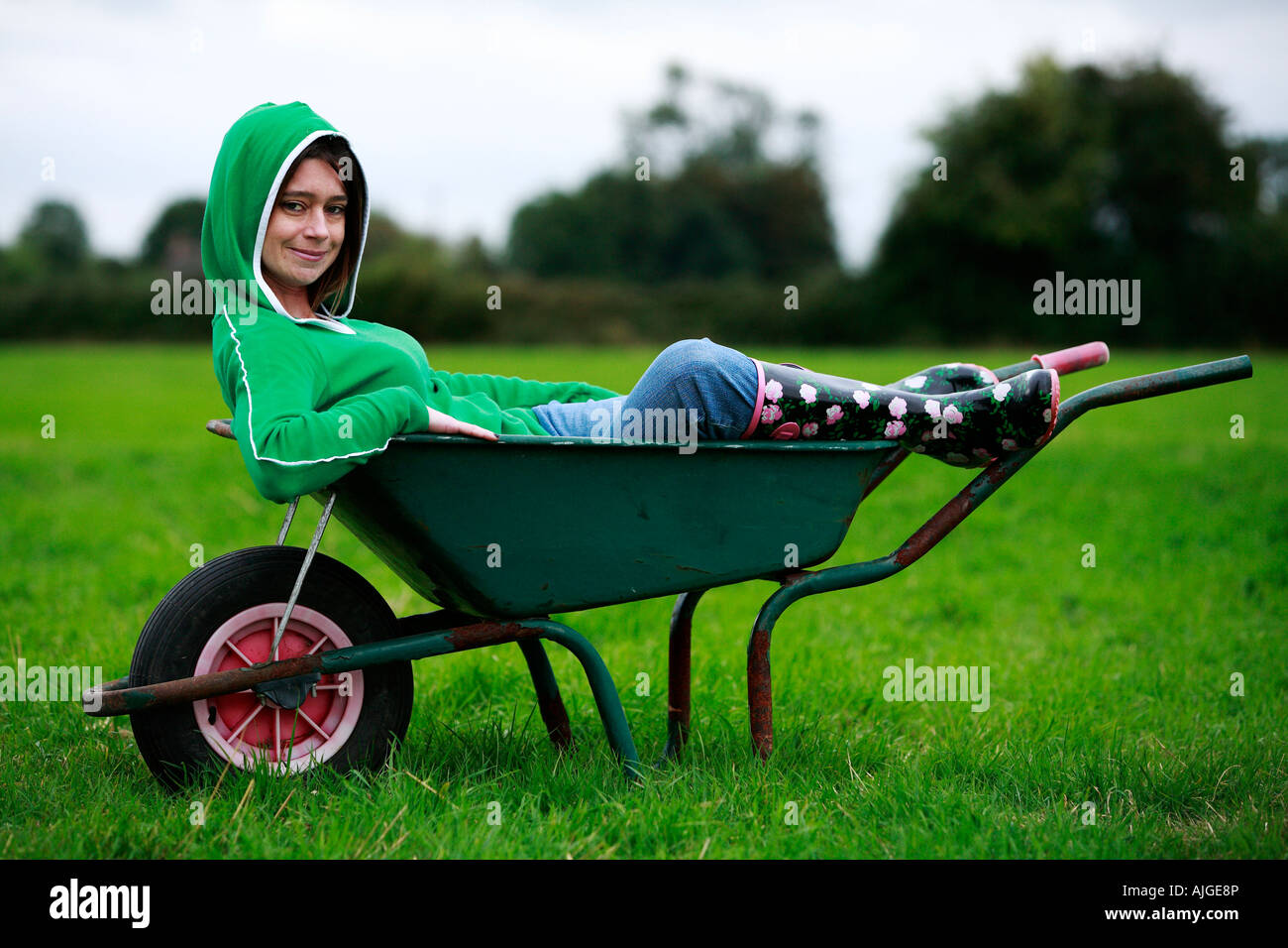 I giovani adulti seduti in una carriola Foto Stock