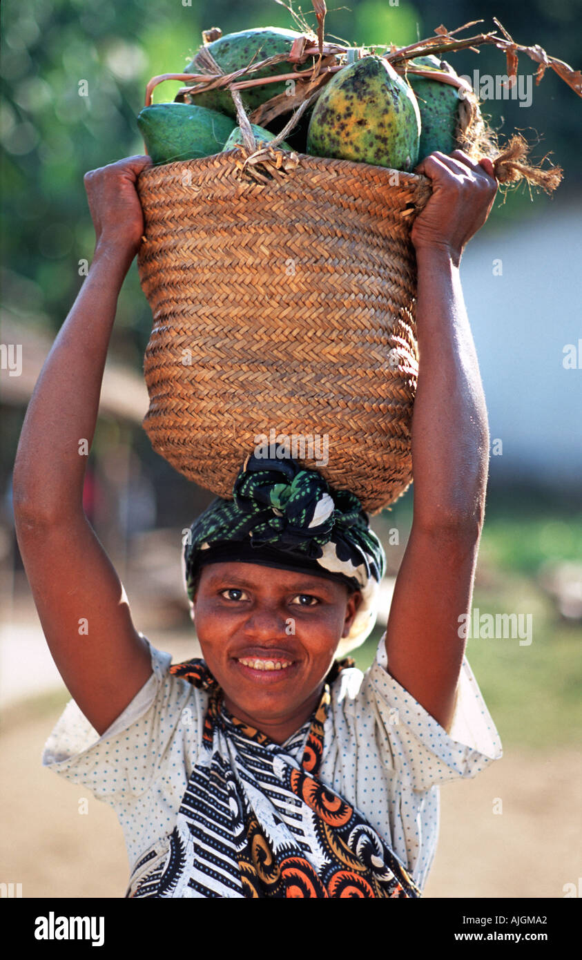Amichevole donna della Tanzania che porta un cesto di frutta di papaia Moivaro Arusha in Tanzania Africa orientale Foto Stock