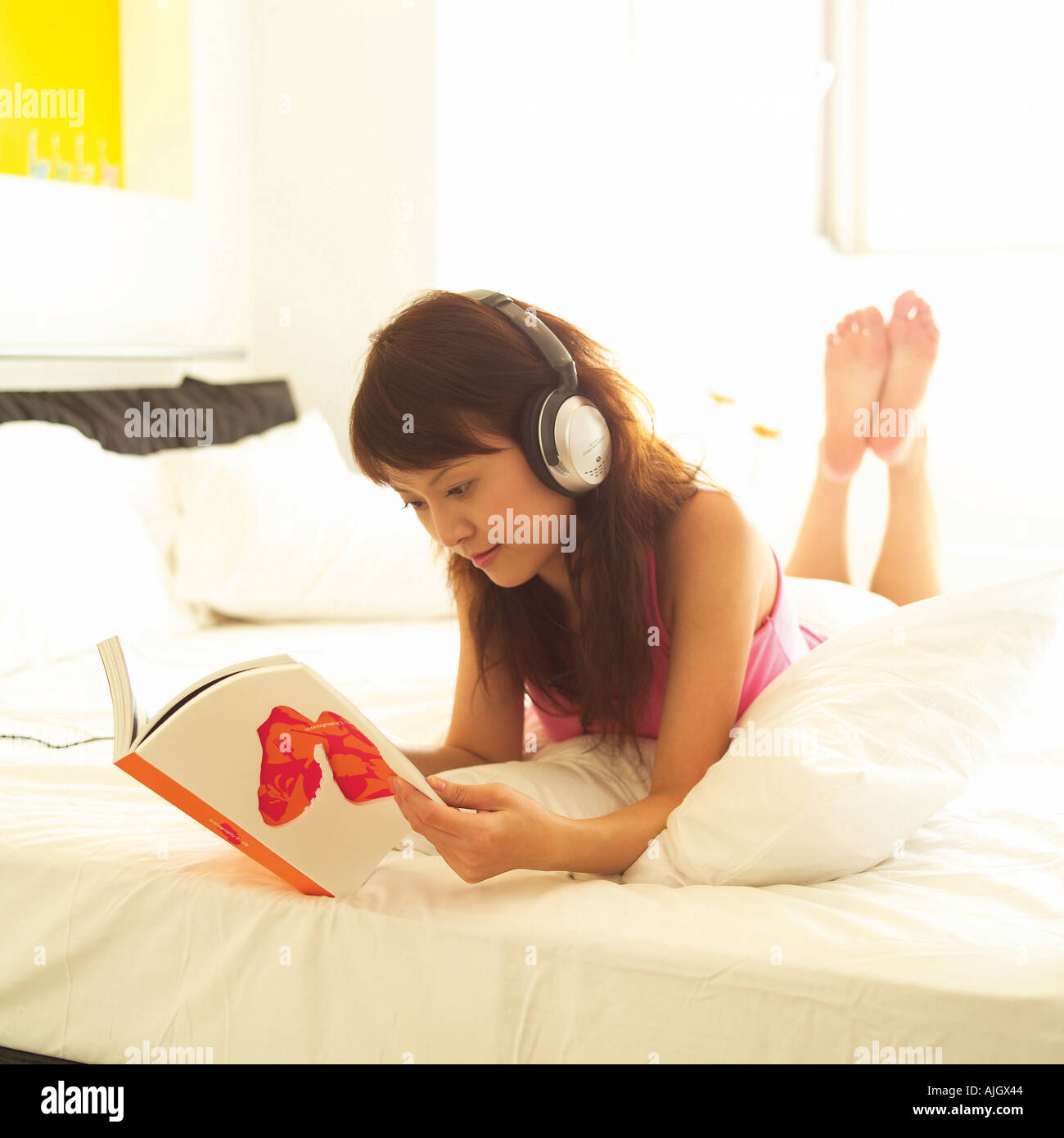 Giovane donna sdraiata sul letto e la lettura di una rivista Foto Stock
