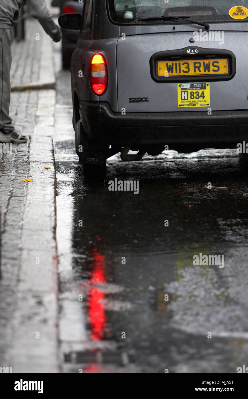 Privata a Londra taxi stile tirato nel lato della strada con pozzanghere di prelevamento tariffa maschio in Belfast City Centre Foto Stock