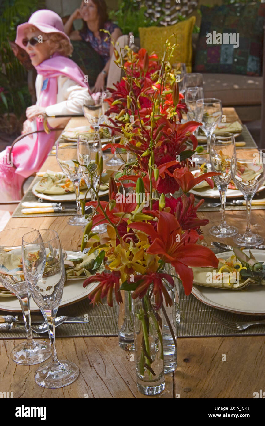 Un patio tabella è impostata per un informale ma elegante cena. Due donne può essere visto in background. Foto Stock