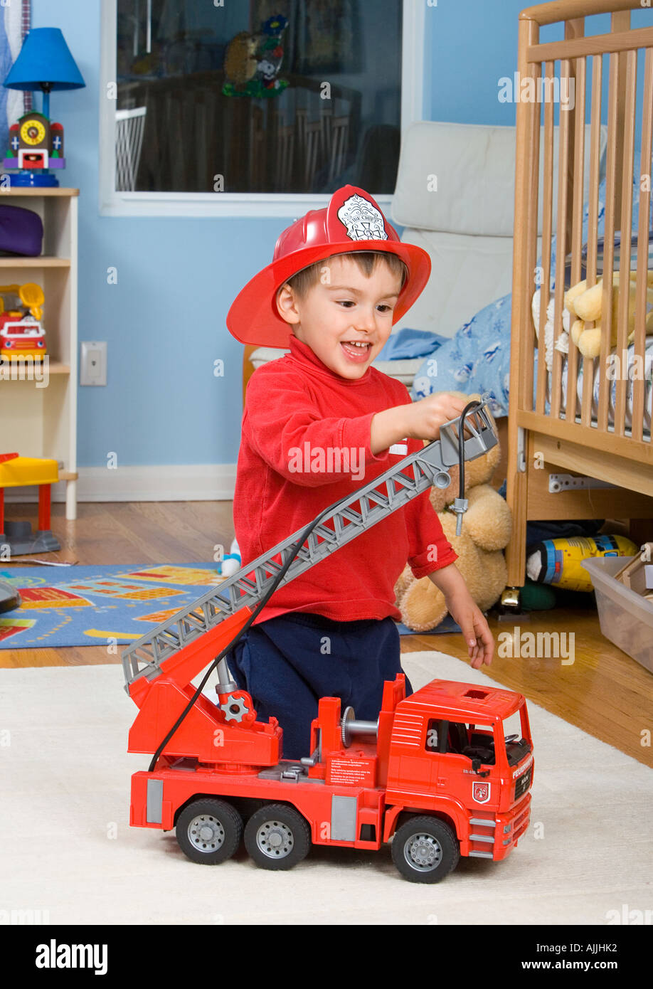Tre anni di vecchio ragazzo gioca con il grande incendio di camion in camera da letto Foto Stock