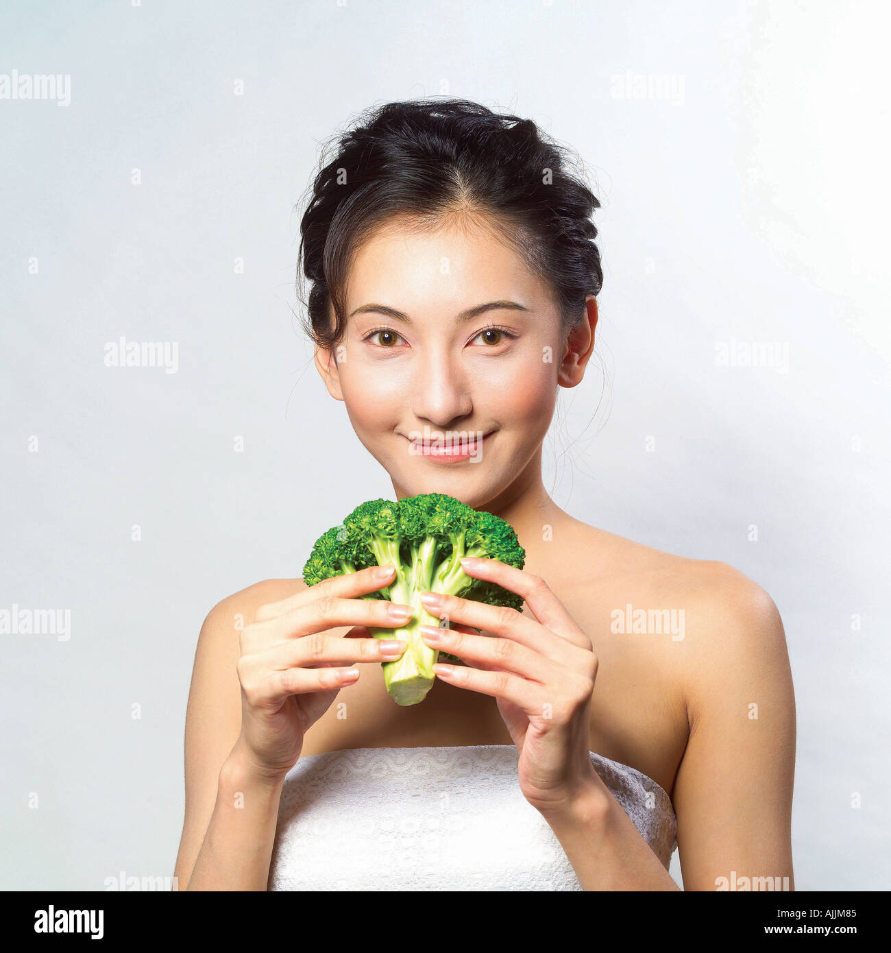 Ritratto di una giovane donna che mantiene una testa di broccoli Foto Stock