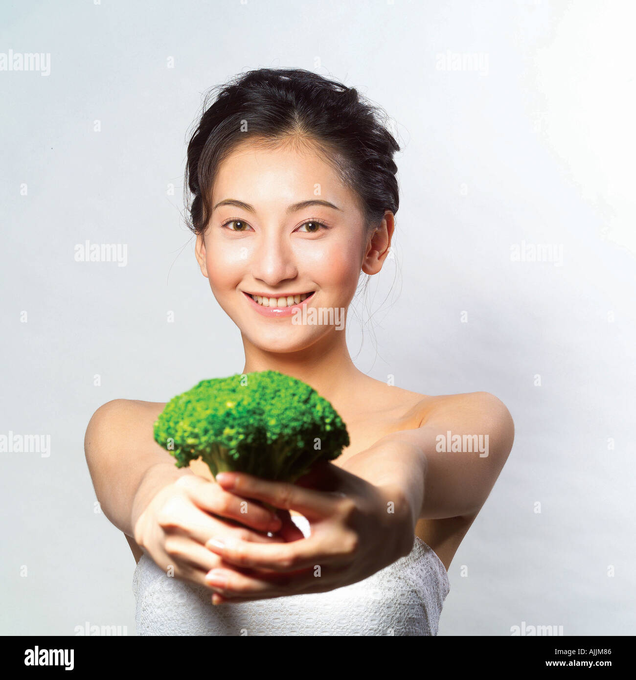 Ritratto di una giovane donna che mantiene una testa di broccoli Foto Stock