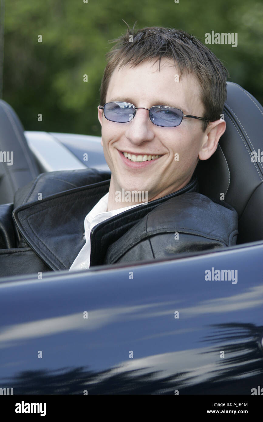 Elegante uomo seduto in un caldo nuova autovettura convertibile durante l'estate Foto Stock