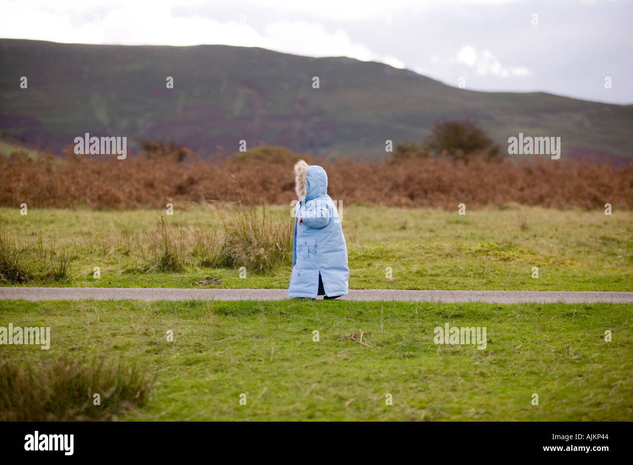 Bambina in una giacca blu di andare a fare una passeggiata sul suo proprio Foto Stock