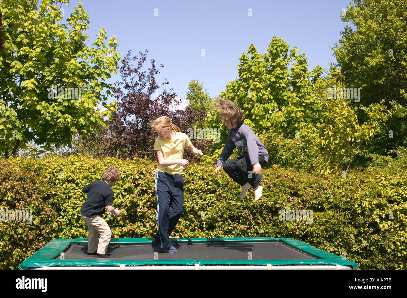 Tre bambini che rimbalza su un trampolino Foto Stock