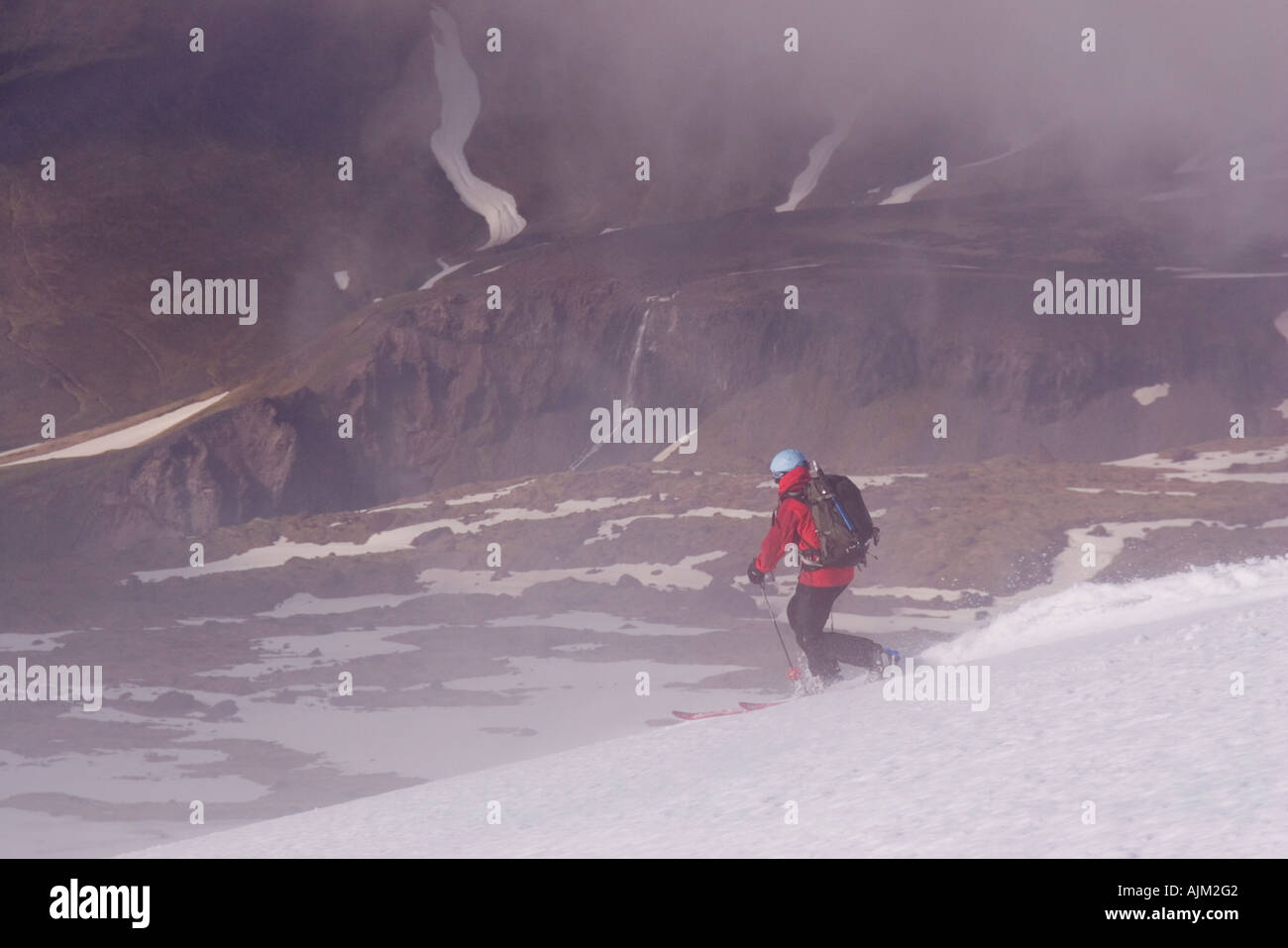 Una donna di sciare su un ghiacciaio al di sopra delle nuvole sul Monte Vsesevidov nel Nelle Isole Aleutine in Alaska Foto Stock