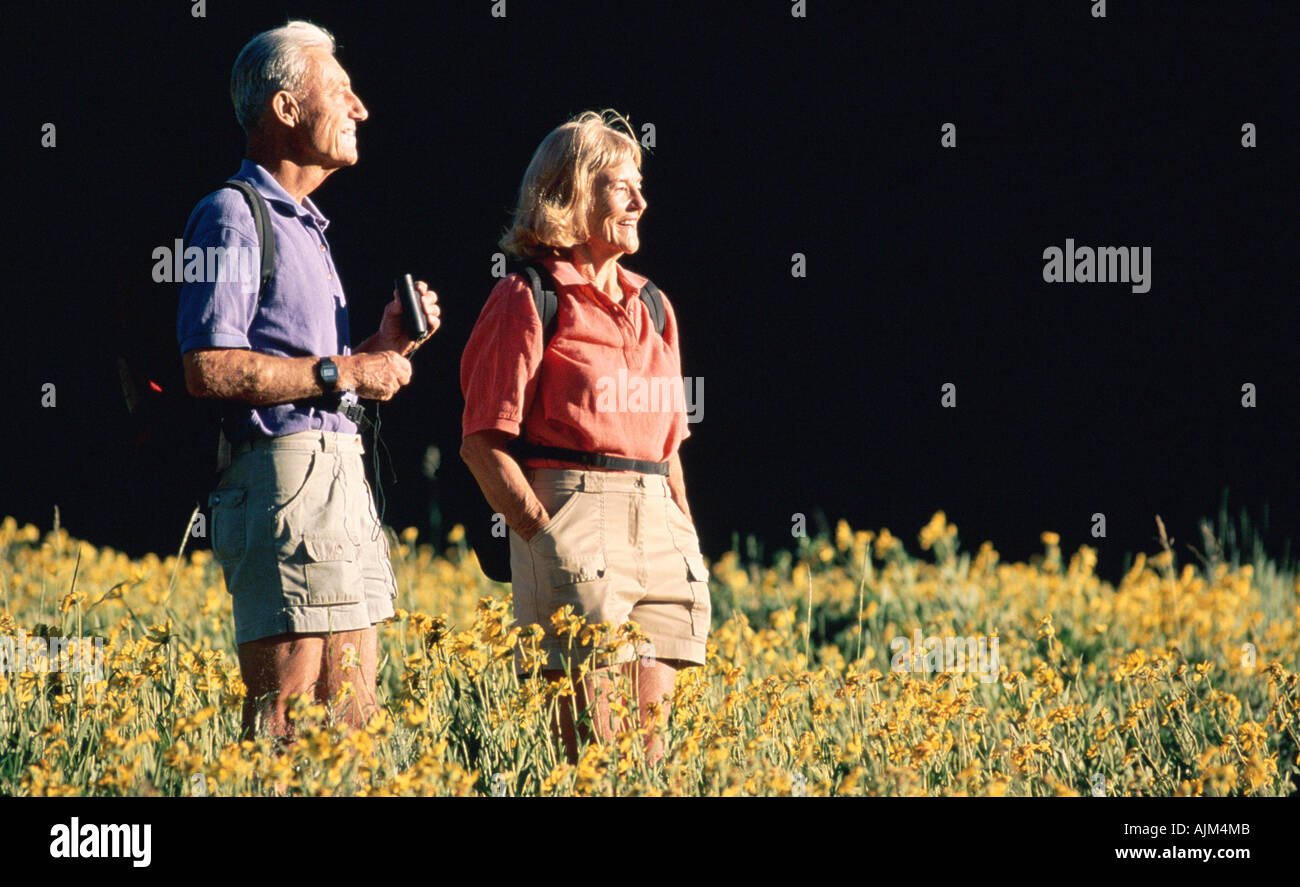 Coppia senior con un binocolo in fiori selvatici Foto Stock Coppia senior con un binocolo in fiori selvatici Foto Stock