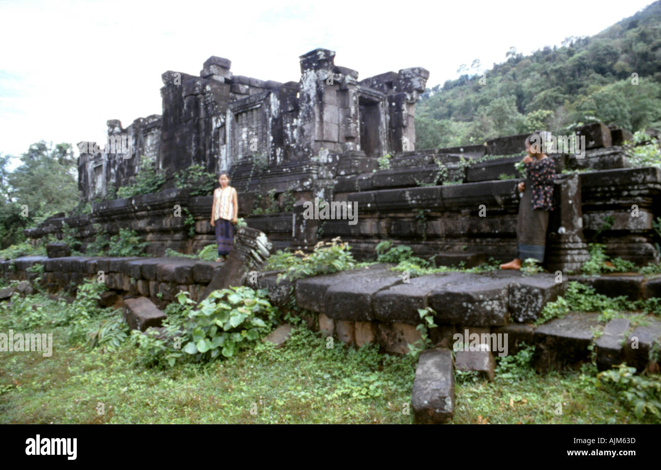Ragazze locali raccogliere verde tra le rovine di Wat Phu sud Laos per aggiungere al fiore offerte per immagini di Buddha Foto Stock