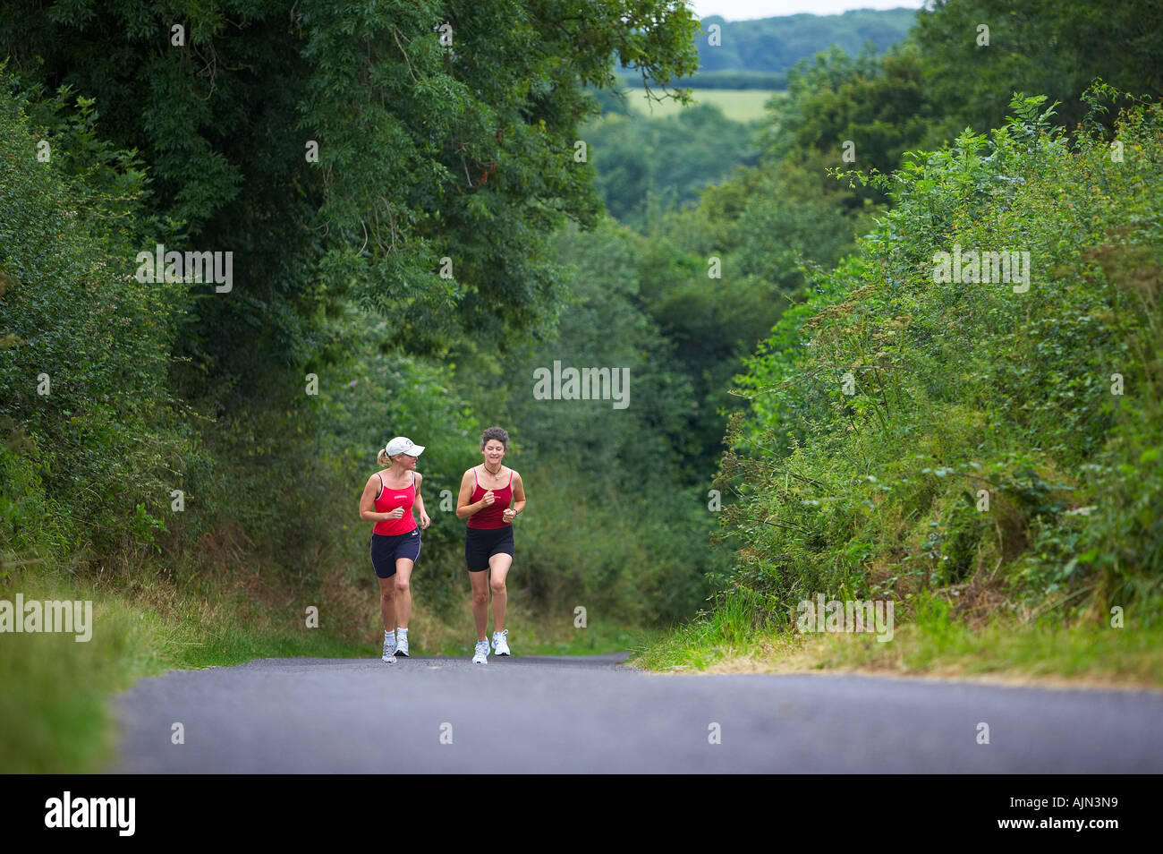 Due donne jogging su un vicolo del paese nr Charlton Horethorne Somerset England Regno Unito MR Foto Stock