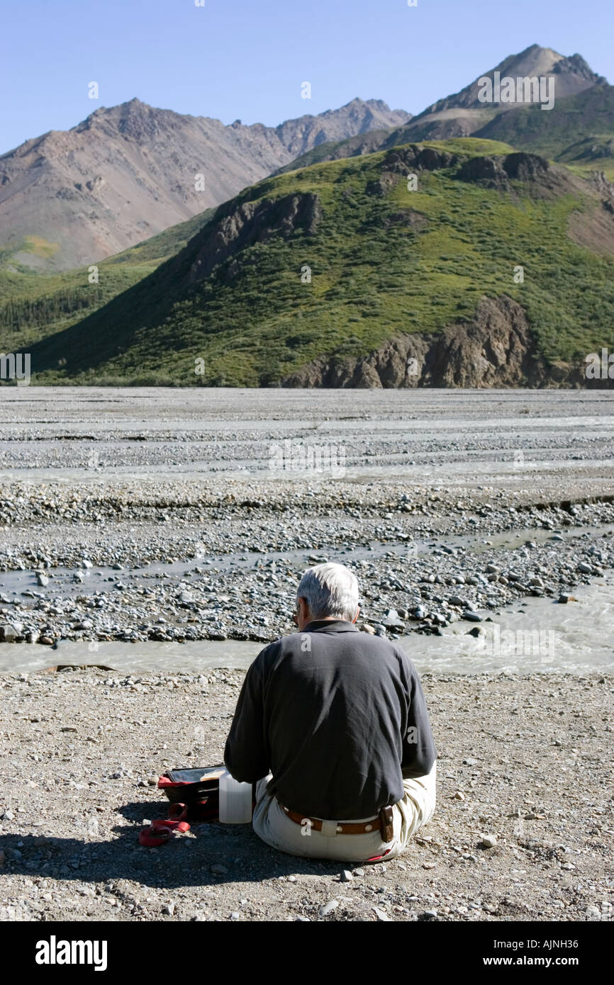 Un visitatore di Denali National Park in Alaska avente il suo pranzo sulle rive del fiume Toklat Foto Stock