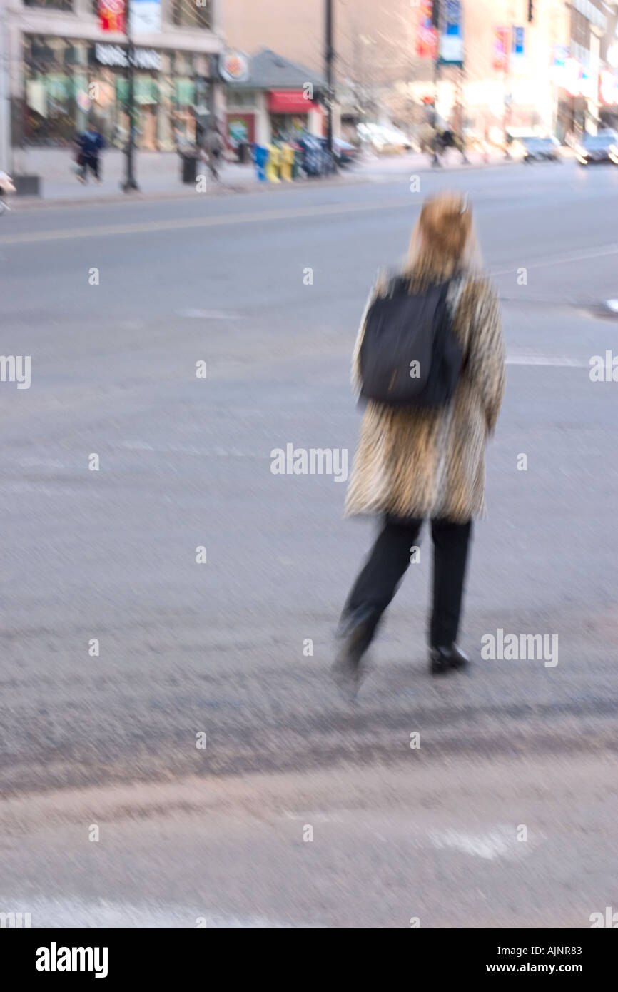 Donna attraversare una strada di città Foto Stock