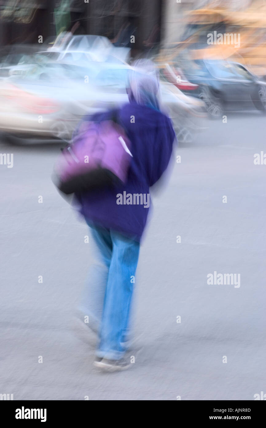 Donna attraversare una strada di città Foto Stock