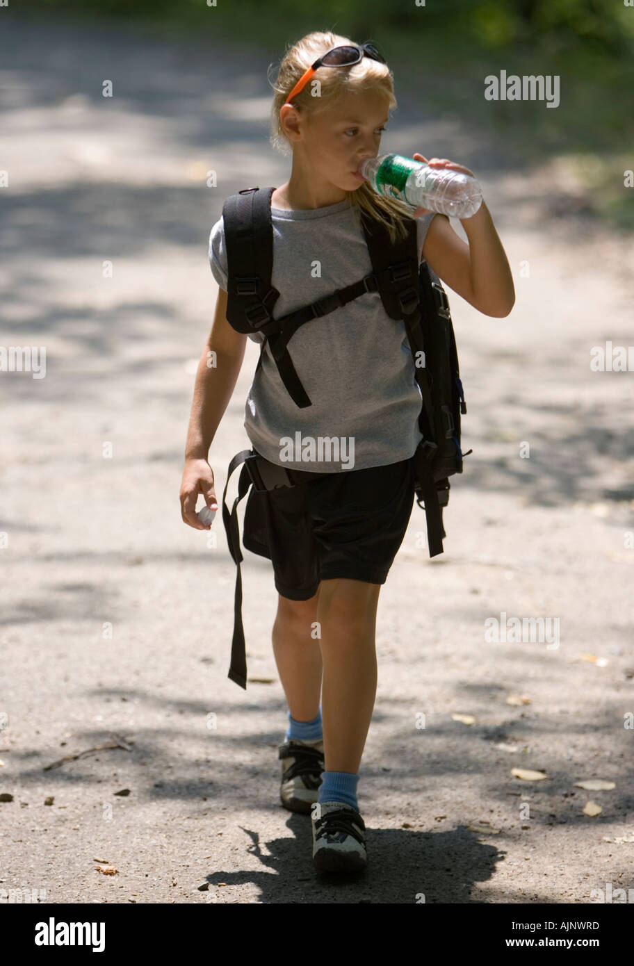 Ragazza di bere da una bottiglia di acqua come lei cammina Foto Stock