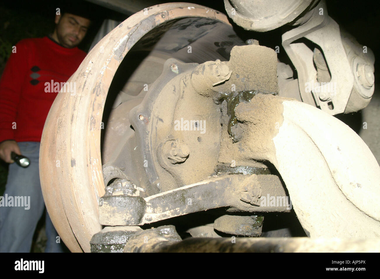Uomo indiano con torcia stanidng accanto a smontaggio bus rotta ruota di notte all'aperto Foto Stock