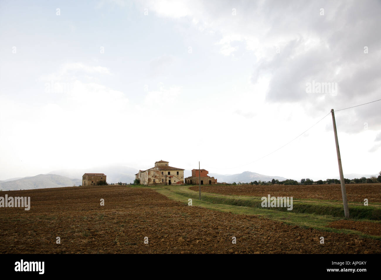 Vista della vecchia e la fattoria abbandonata nel paesaggio toscano. La città di Cortona è visibile sulla destra hill in background. Foto Stock