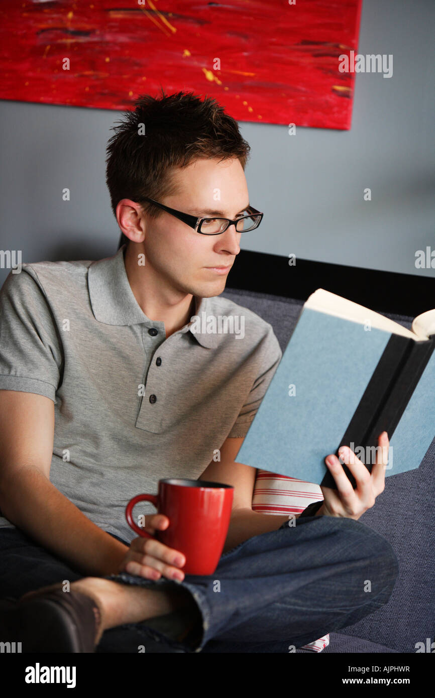 Uomo di lettura con una bevanda calda Foto Stock