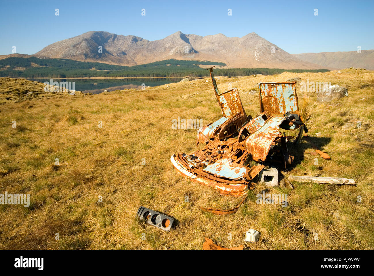 Abbandonati macchinari agricoli nei pressi di Lough Inagh con Bencorr e le cime orientali dei dodici Bens di Connemara alle spalle, County Galway, Irlanda Foto Stock