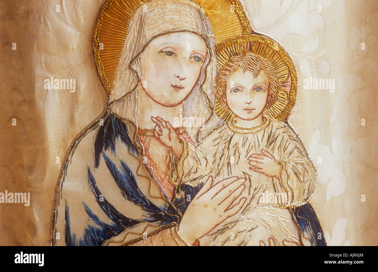 Dettaglio ricamato dell immagine della Vergine Maria tenendo il Bambino Gesù Cristo nei colori smorzati sul panno beige Foto Stock