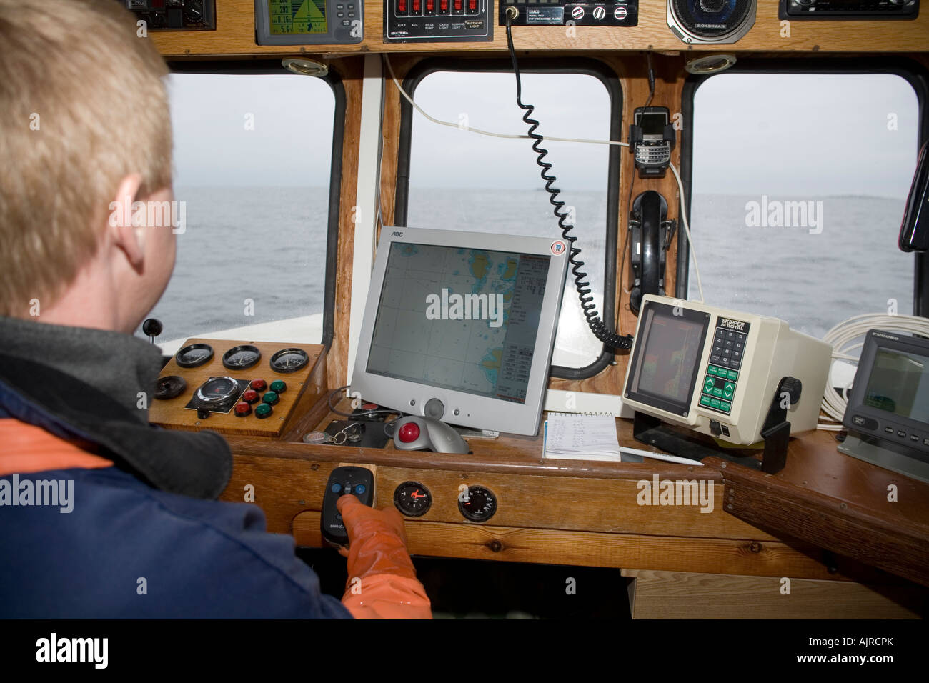 Uomo a bordo della sua barca. GPS e sirene di echo sono grandi gli ausili alla navigazione in poco profonde acque costiere della Svezia occidentale Europa Foto Stock