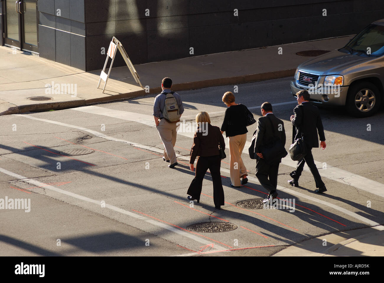Foto distanti di un gruppo di uomini di affari che attraversando a piedi attraversando una strada, dall'alto. Foto Stock