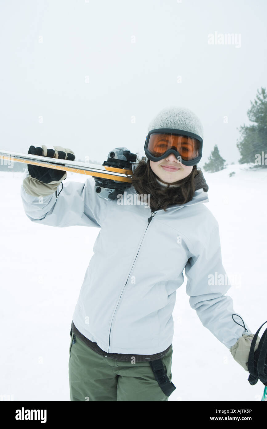 Ragazza adolescente che trasportano gli sci in spalla, sorridente
