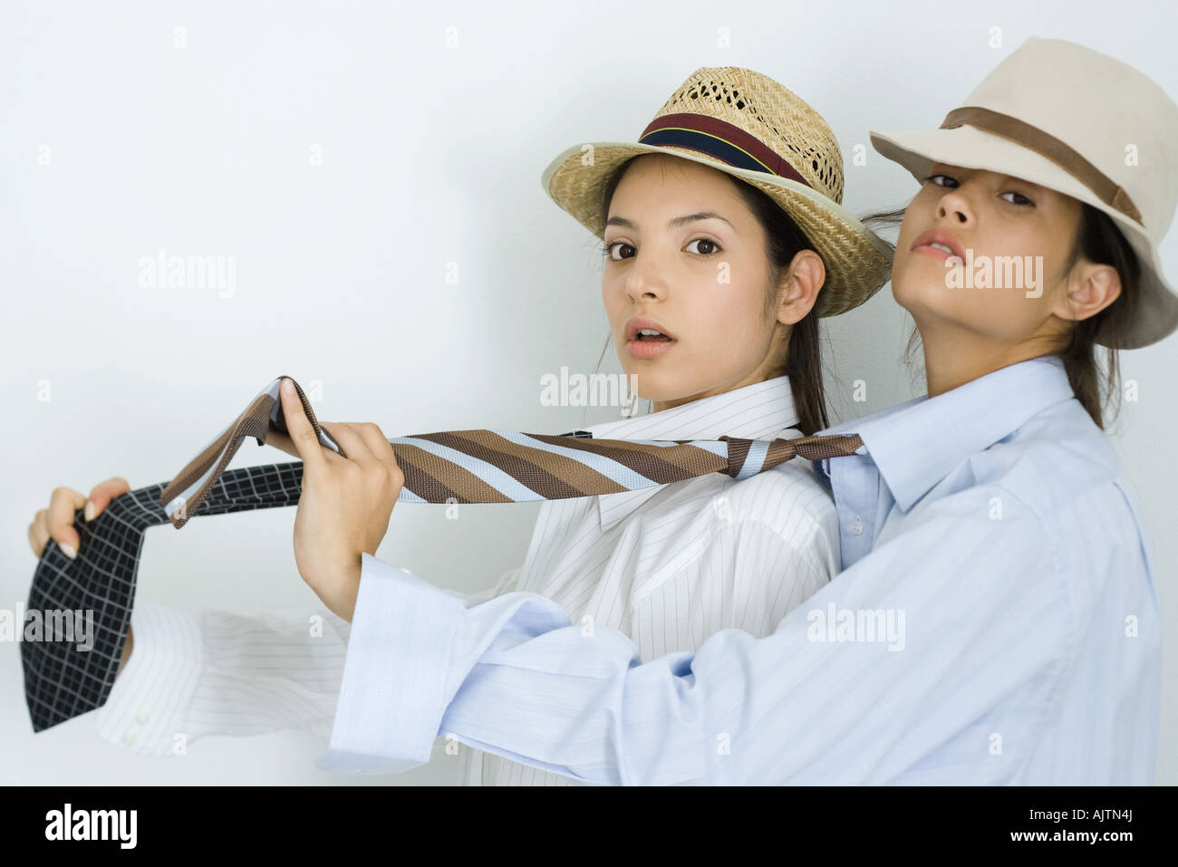 Due giovani amici di sesso femminile vestito di cappelli e cravatte, uno  dietro l'altro, guardando la fotocamera Foto stock - Alamy