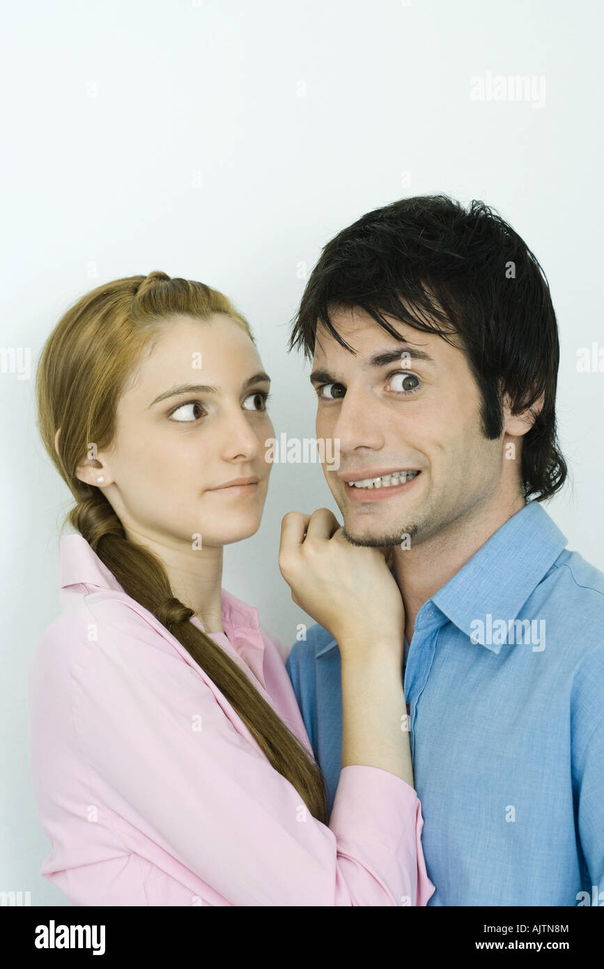 Coppia giovane insieme, l'uomo facendo facce a fotocamera, donna che guarda l'uomo Foto Stock