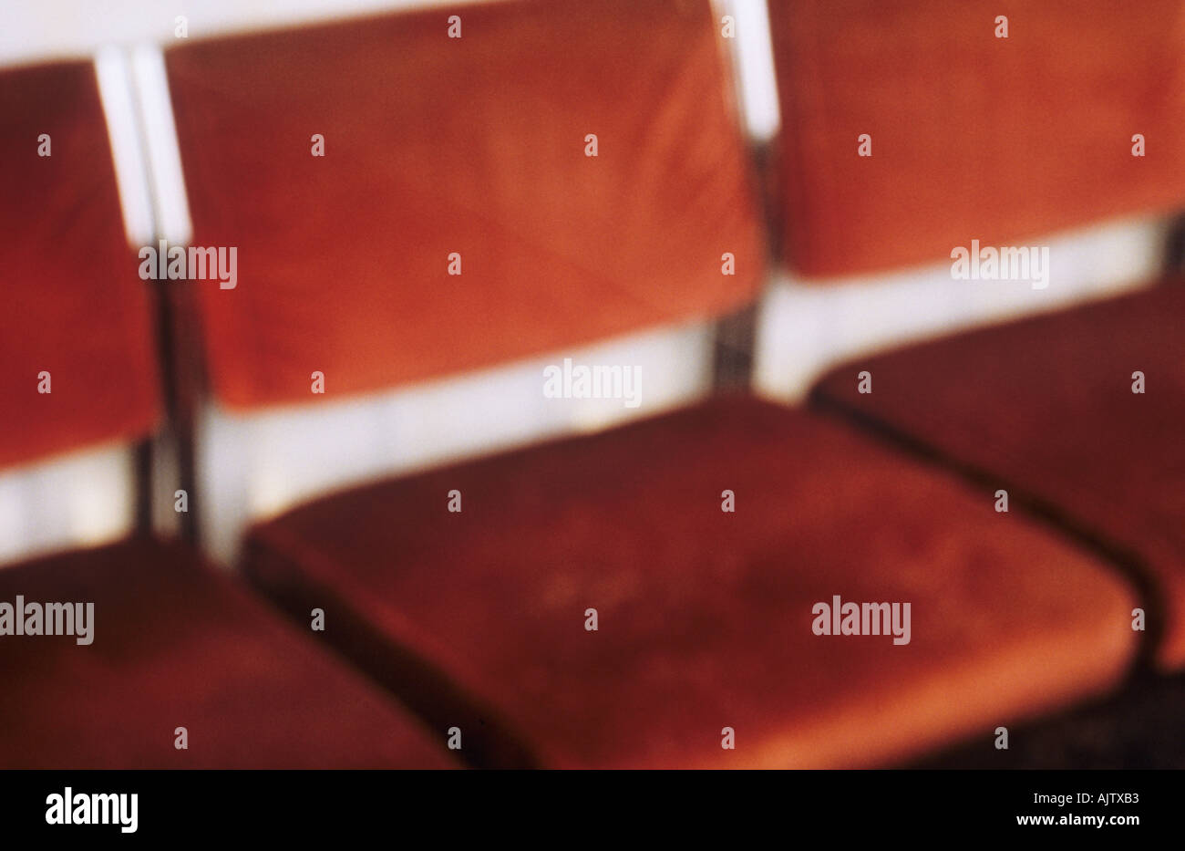 Soft focus particolare di tre profondo velluto rosso sedie in fila allineati contro un muro bianco Foto Stock
