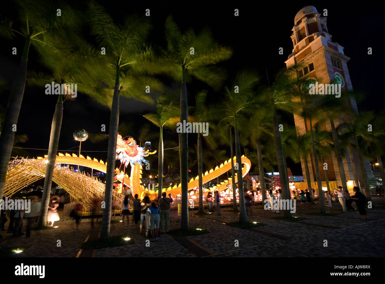 I turisti circondano un complesso drago illuminato in banchina Parco di Kowloon di notte Foto Stock